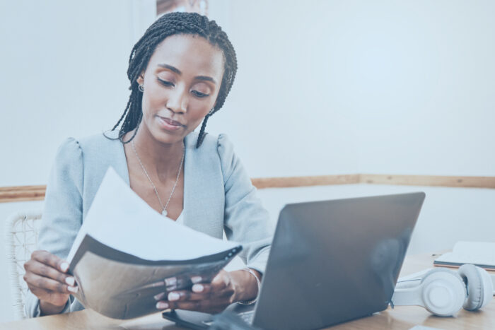 Femme regardant des documents devant un ordinateur portable