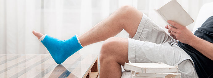 Homme ayant un pied dans le plâtre en train de lire un livre